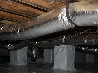 Insulated HVAC ducts running through a crawlspace under exposed wooden beams