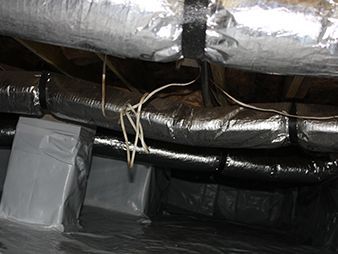 Insulated ductwork and exposed wires in a ceiling crawlspace, with taped connections and gray ventilation tubes