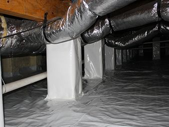 Attic crawl space with insulated ducts, white support posts, and plastic-covered floor