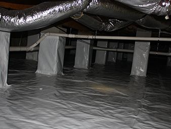 Crawlspace with plastic sheeting on the floor, insulated ducts overhead, and support posts.