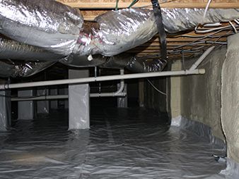Crawlspace with silver insulated ducts, exposed pipes, and black plastic moisture barrier on the floor