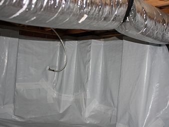 Plastic sheeting covering exposed ductwork and wall framing in a basement or crawl space