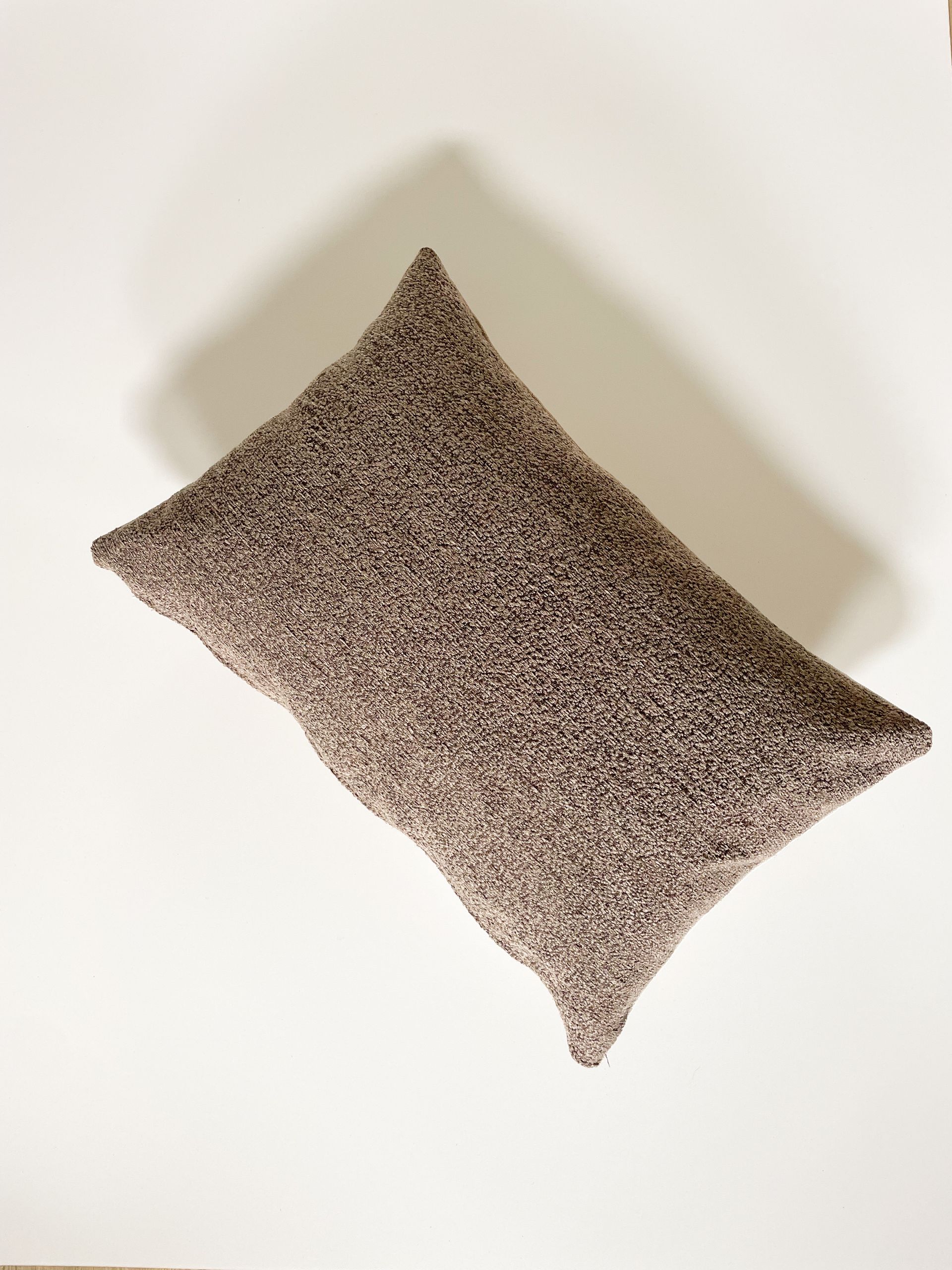 Tweekleurig geweven sierkussen, beige en gebroken wit, op een witte achtergrond.