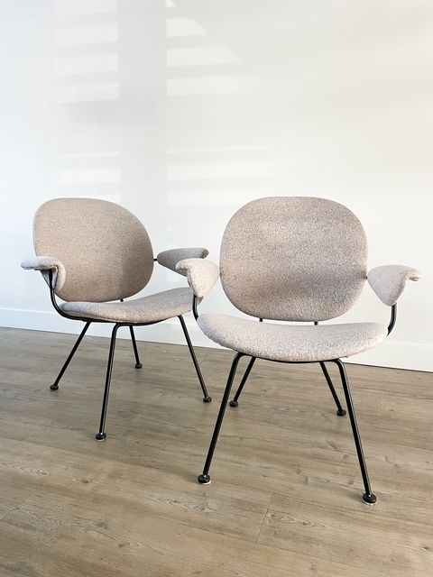 Twee beige stoelen op een lichte houten vloer tegen een witte muur.