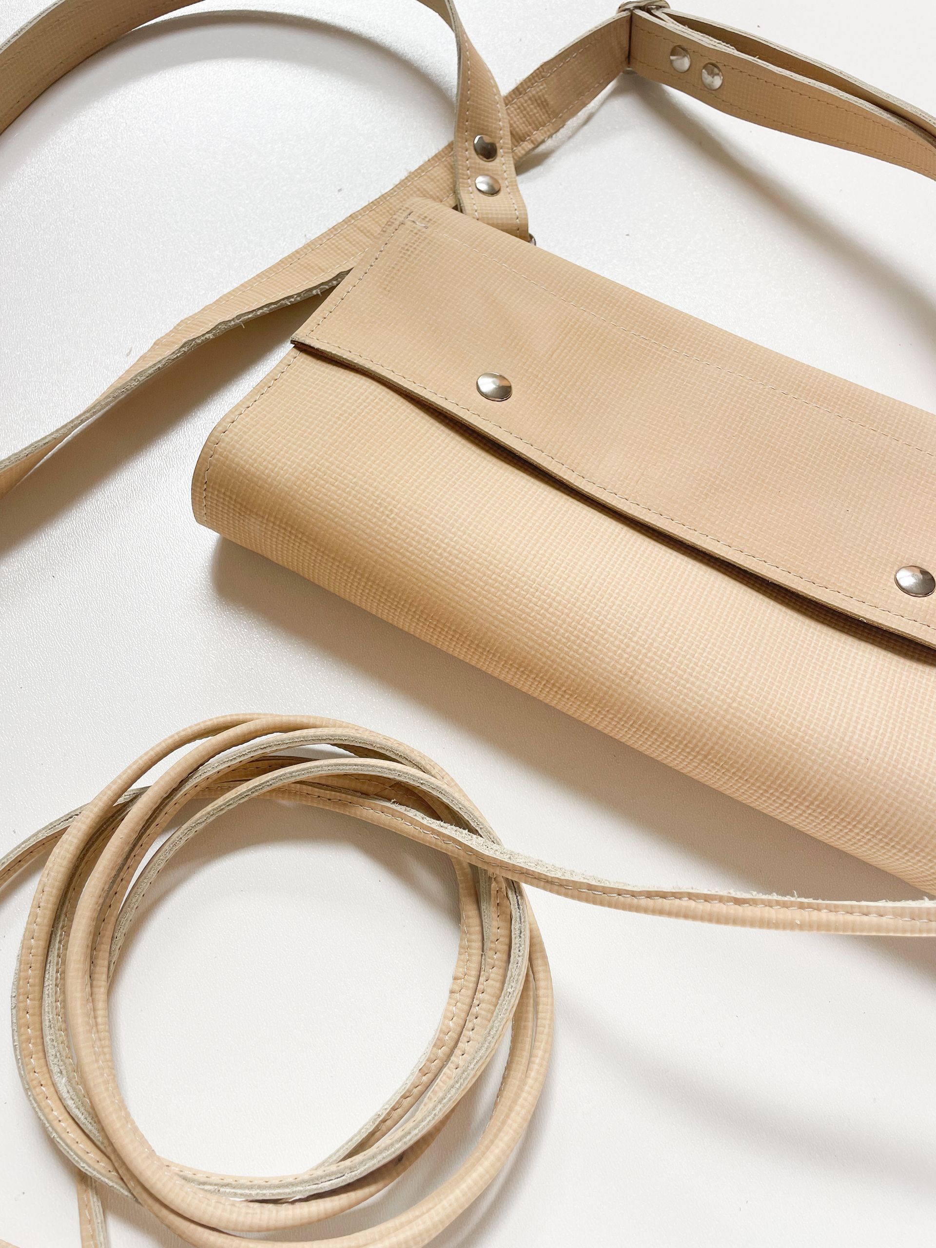 Beige leren crossbodytas met schouderband op een witte achtergrond
