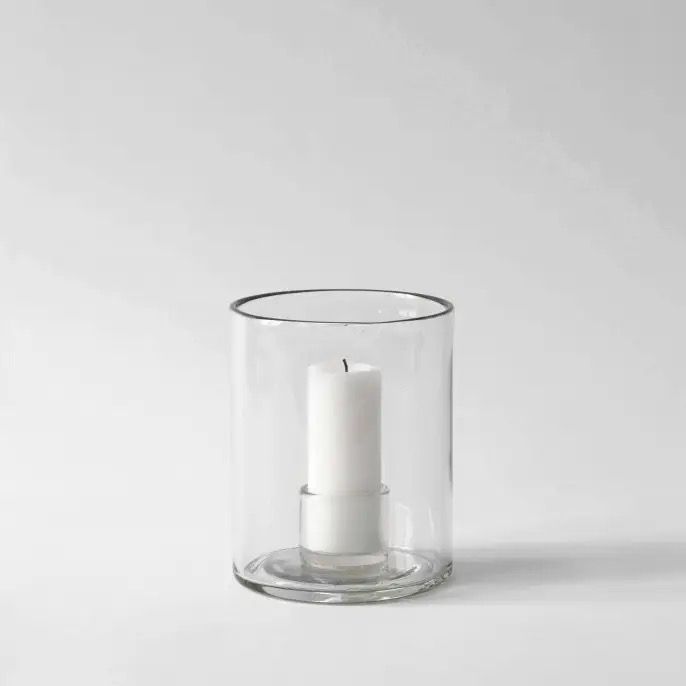 Doorzichtige glazen cilinder met een klein glazen kopje erin op een witte achtergrond.