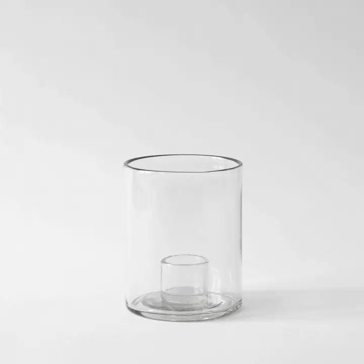 Doorzichtige glazen cilinder met een klein glazen kopje erin op een witte achtergrond.