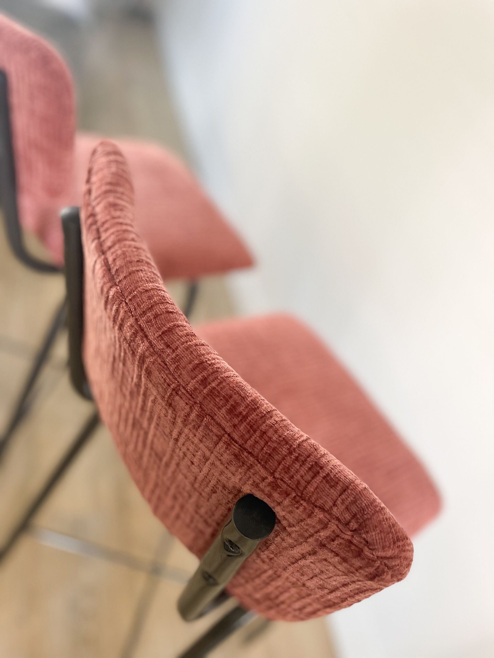 Roze gestoffeerde stoelen staan ​​op een rij, van de zijkant gezien in een kamer.