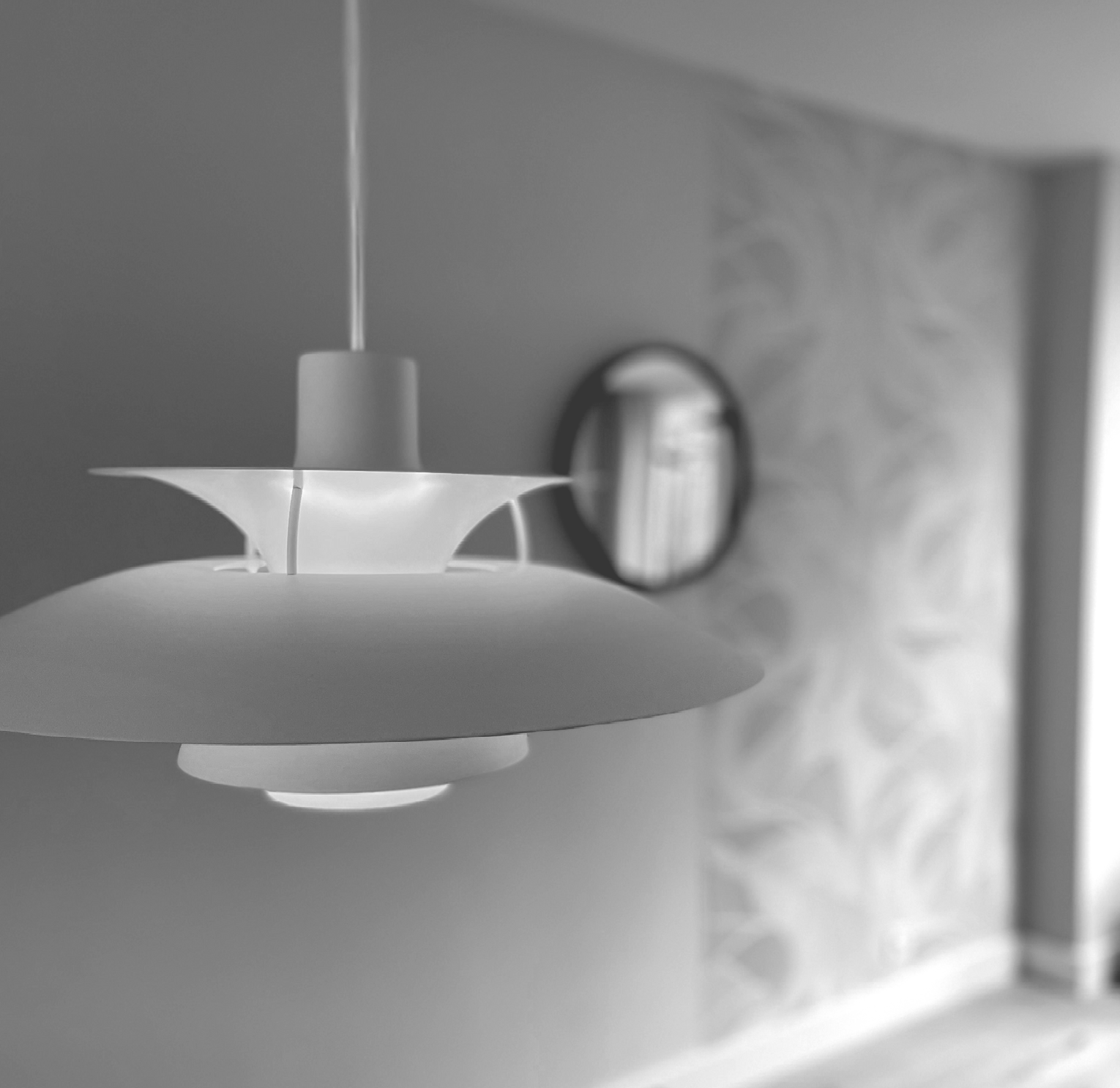 Moderne witte hanglamp in een sfeervol verlichte hal met een ronde wandspiegel.
