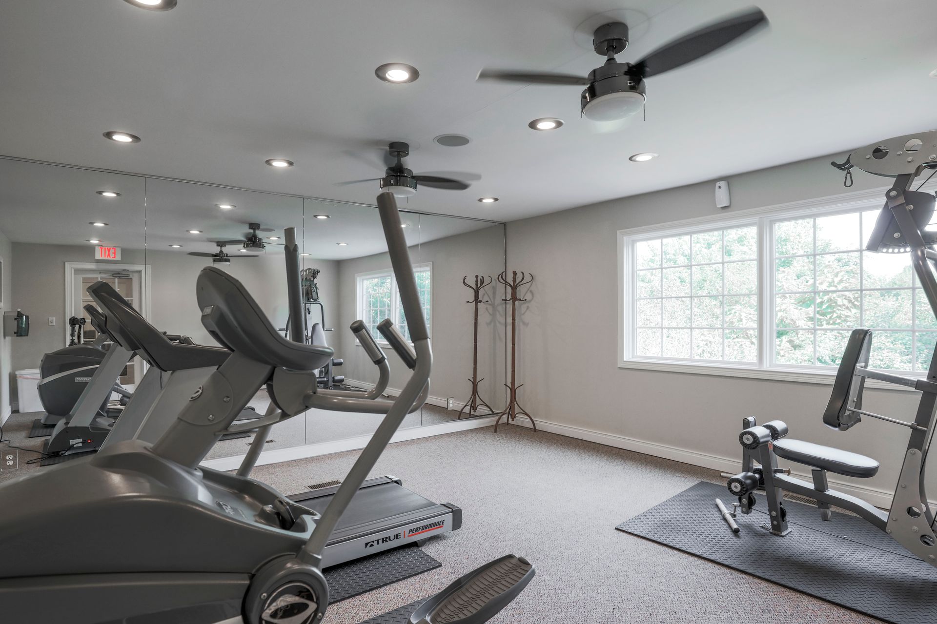 Bright gym room with treadmills, exercise bike, weights, and large windows