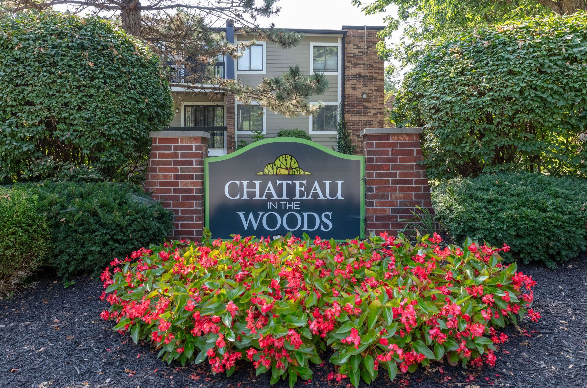 Chateau Woods community sign in front of flowers and manicured shrubs at an apartment complex entrance