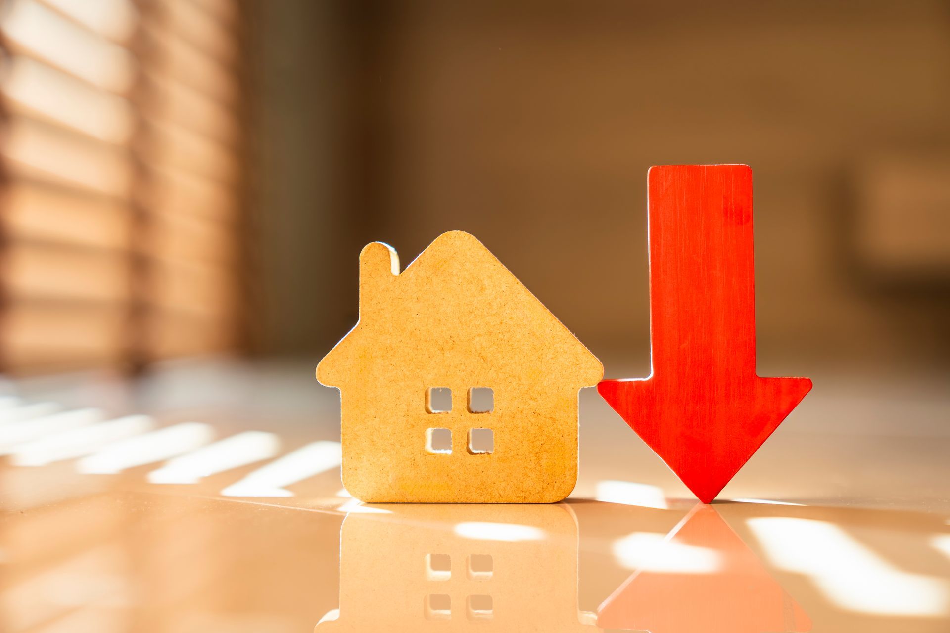 Wooden house icon beside a red downward arrow on a glossy surface