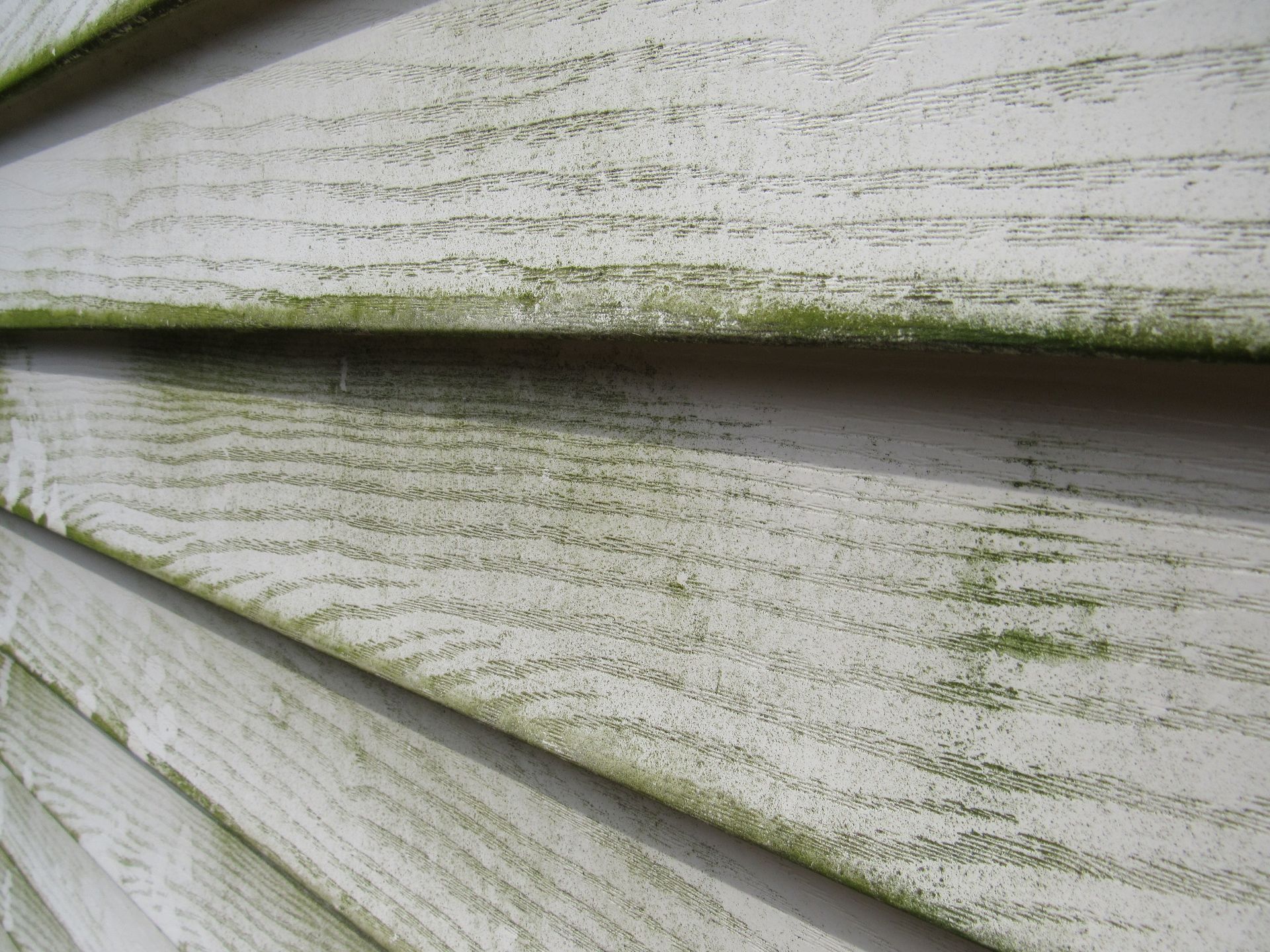Close-up of overlapping pale green and white wooden planks with textured paint