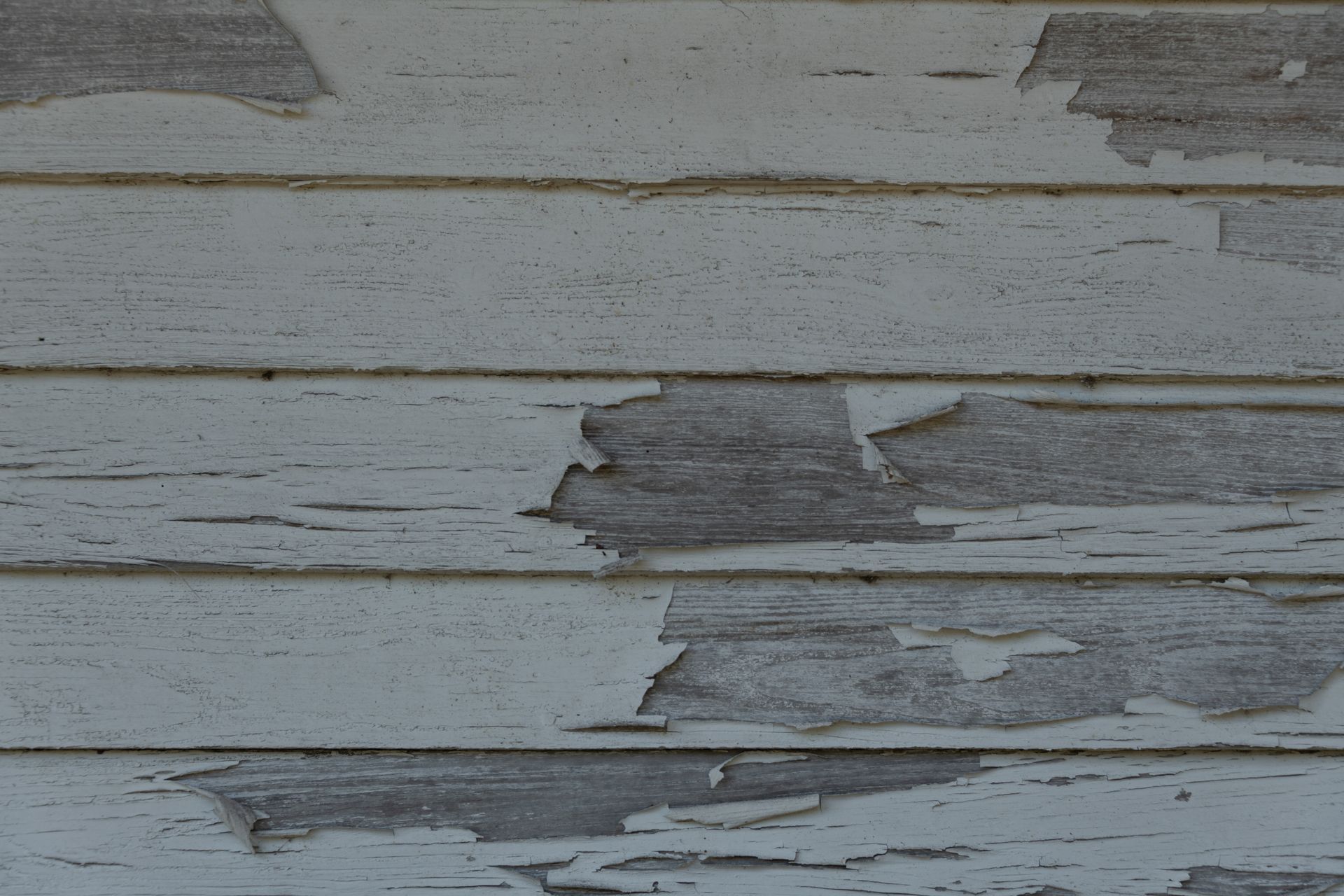 Peeling white painted wood boards with cracked, weathered paint.