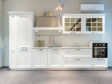 Modern white kitchen with cabinets, island-style counters, sink, oven, and pendant lighting