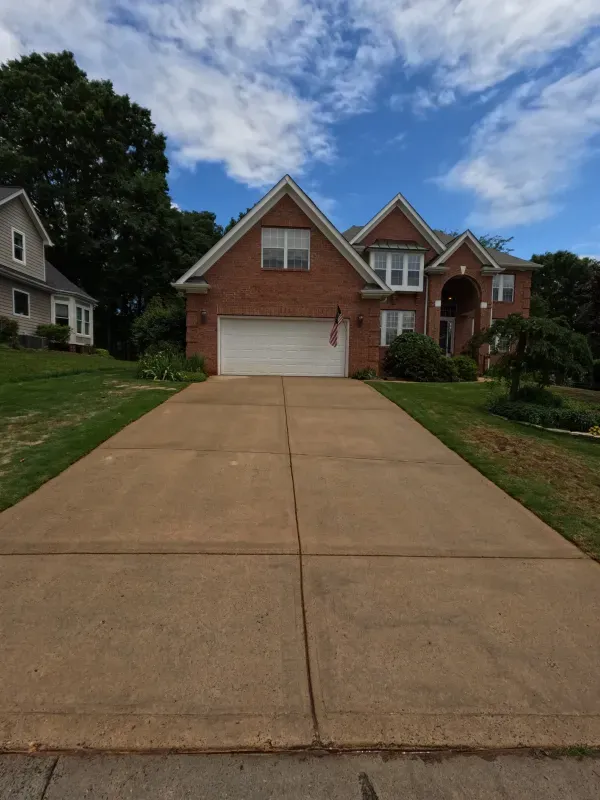A driveway leading to a brick house with a white garage door