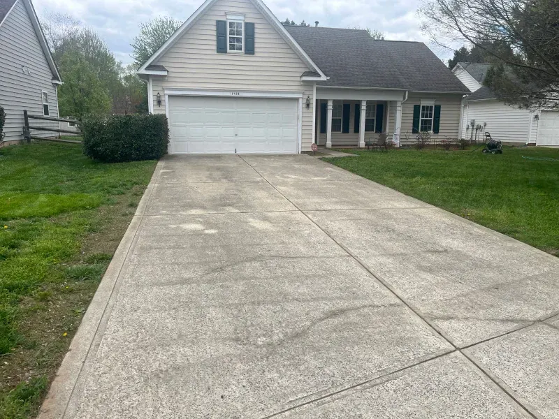 A concrete driveway leading to a house with a garage.