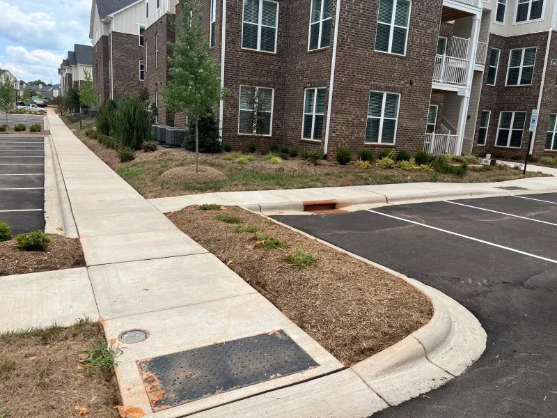 A sidewalk leading to a parking lot next to a brick building.
