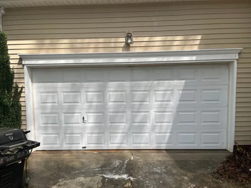 A white garage door is sitting in front of a house.