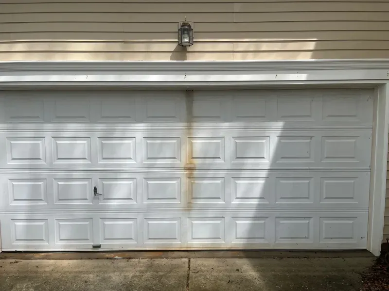 A white garage door is sitting on the side of a house.