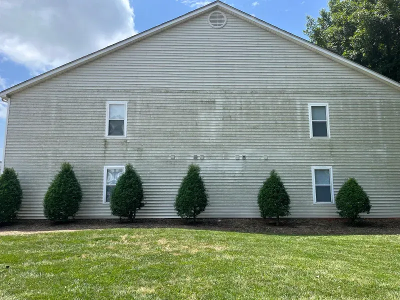 A large white house with a lot of windows and bushes in front of it.