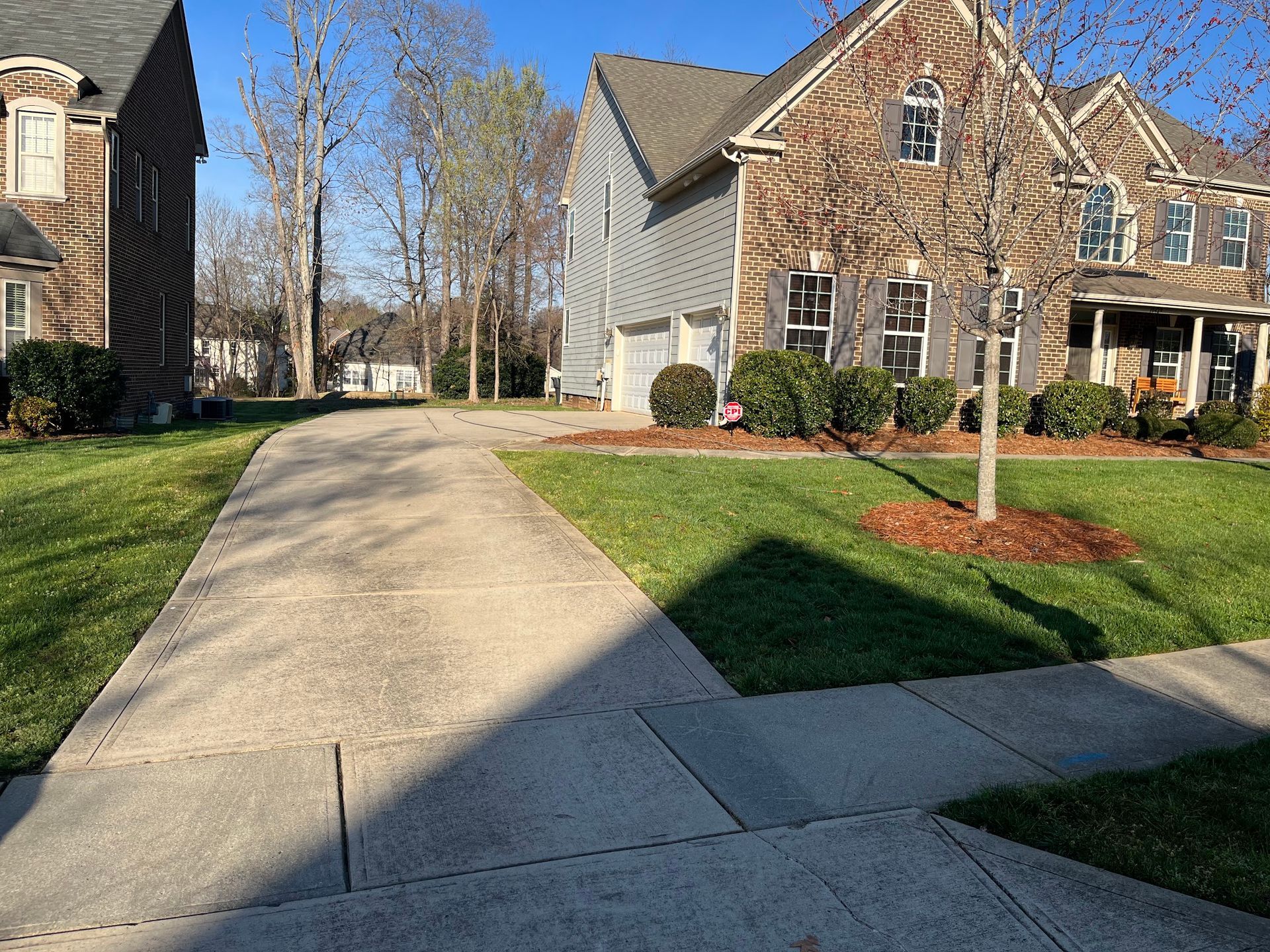 A concrete driveway leading to a house in a residential neighborhood.