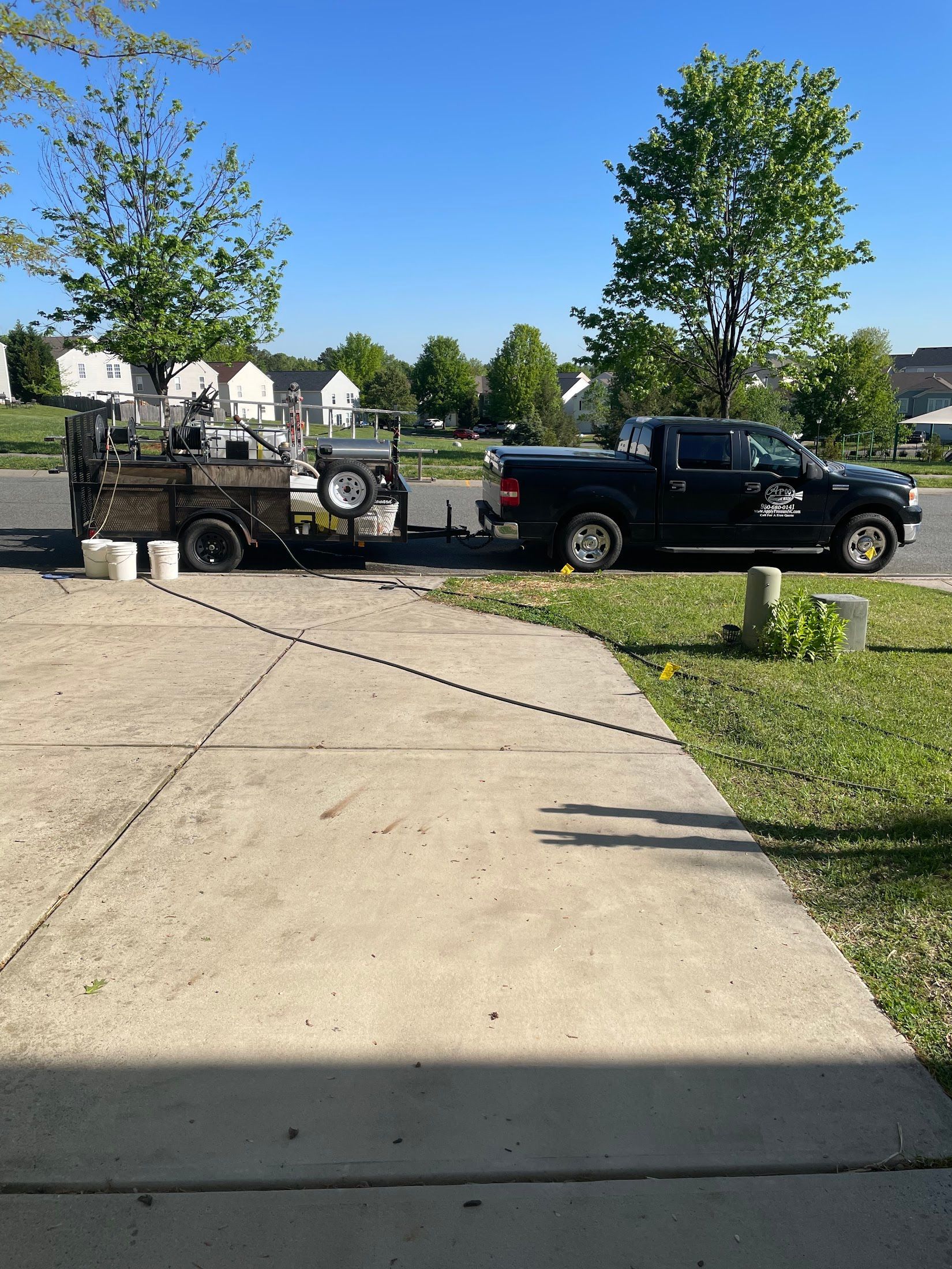 A black truck is parked in a driveway next to a trailer.