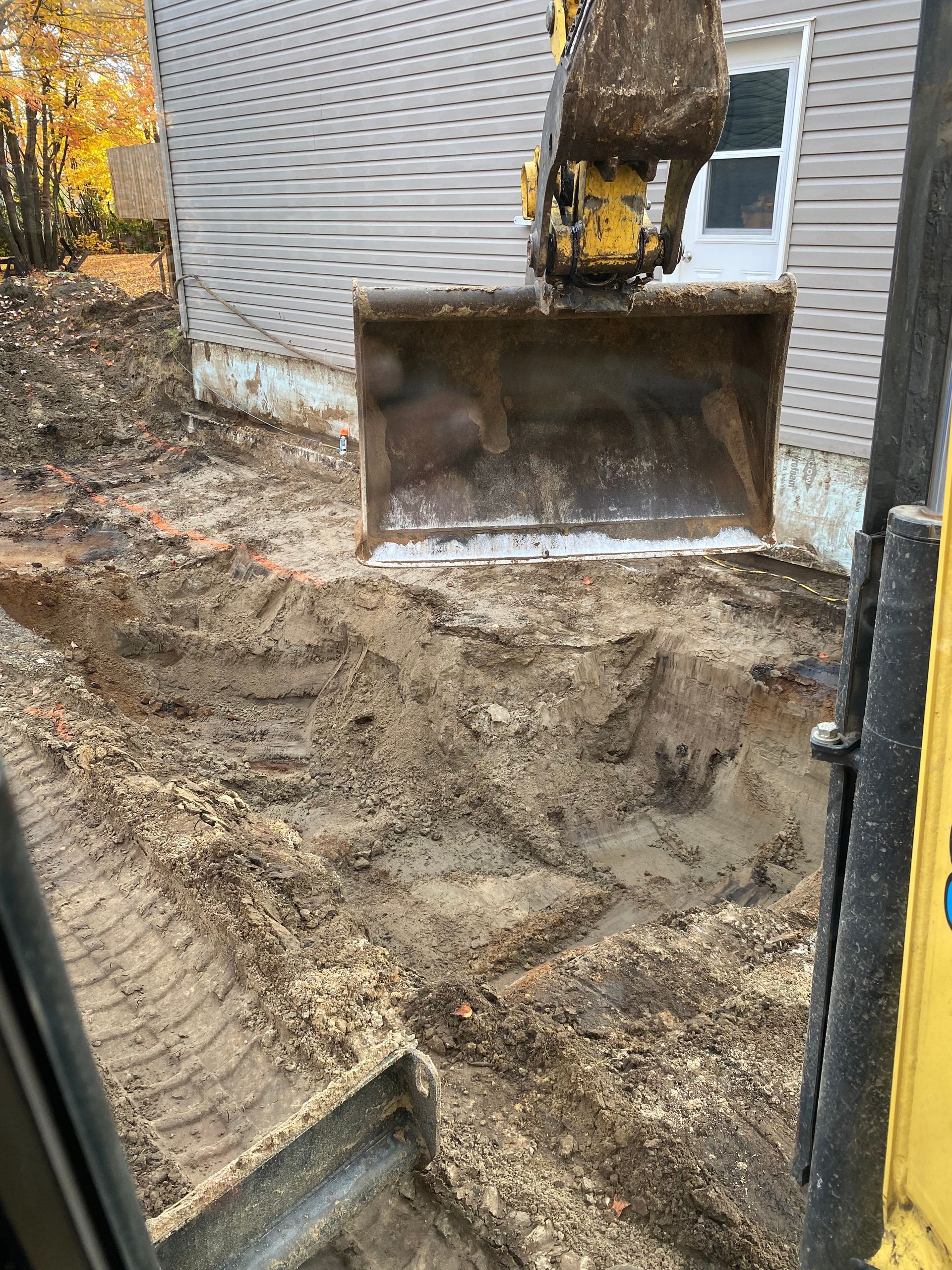Un bulldozer déplace de la terre devant une maison.