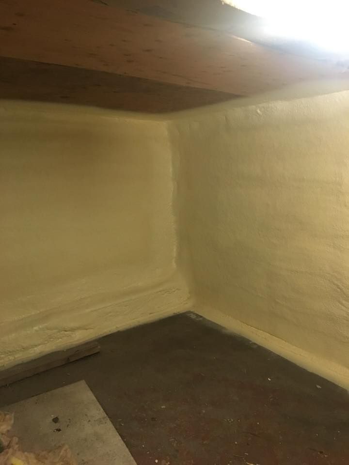 Empty basement corner with beige walls, dark floor, and a low wooden ceiling