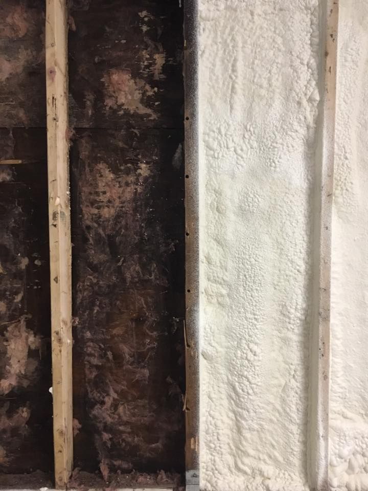Exposed wall framing beside a white textured wall and dark insulation.