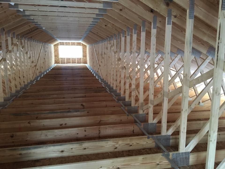 Wooden tunnel-style corridor with cross-braced walls and steps leading to a bright opening