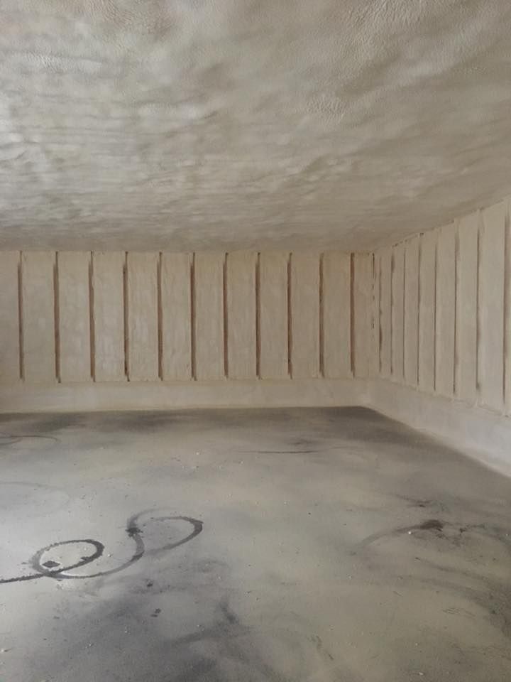 Empty beige room with ribbed walls and a concrete floor, showing a black cable on the ground