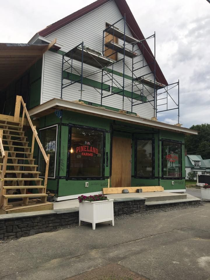 Street-side building with green storefront, scaffolding, and wooden stairs on the left