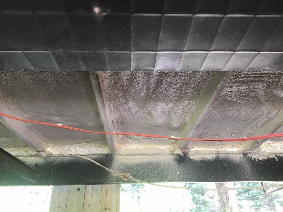 Underside of a roof with dark panels, a red cable, and light leaking through seams