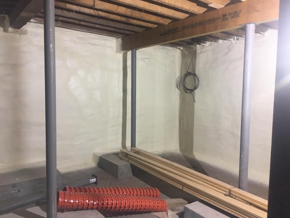 Industrial room with metal shelving, coiled red tubing, and pipes against white walls.
