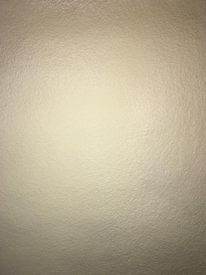Beige textured wall with a bright light reflection in the center