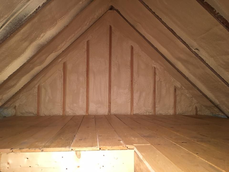 Empty wooden attic interior with exposed rafters and slanted ceiling