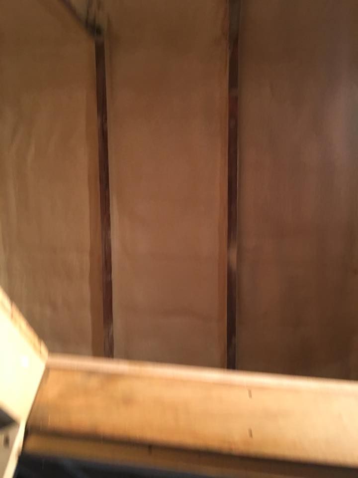 Wooden wall panels and a light-colored bench or ledge in a dim interior corner.