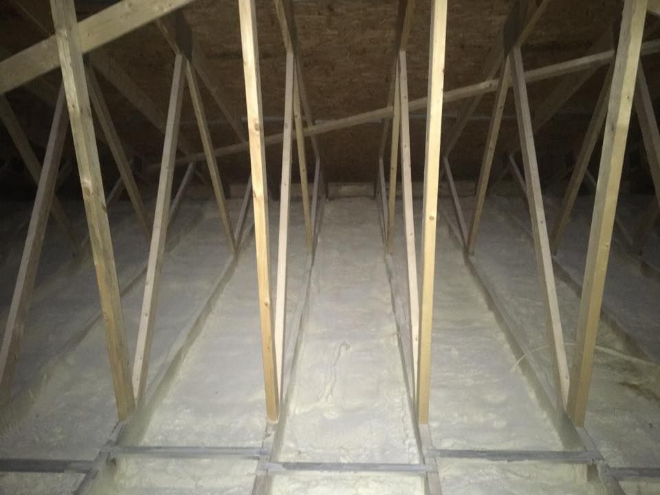 Attic interior with exposed wooden roof trusses and insulation on the floor