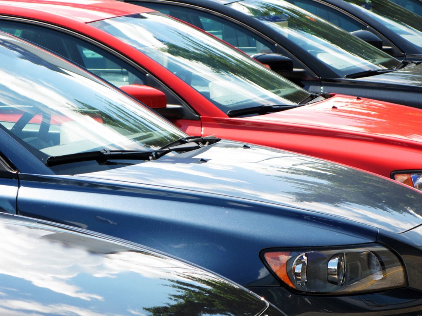 Line of colorful cars parked outdoors, red and blue vehicles prominent.