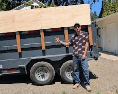 Owner of PRP Junk Removal Chris stands next to a dumpster trailer. 