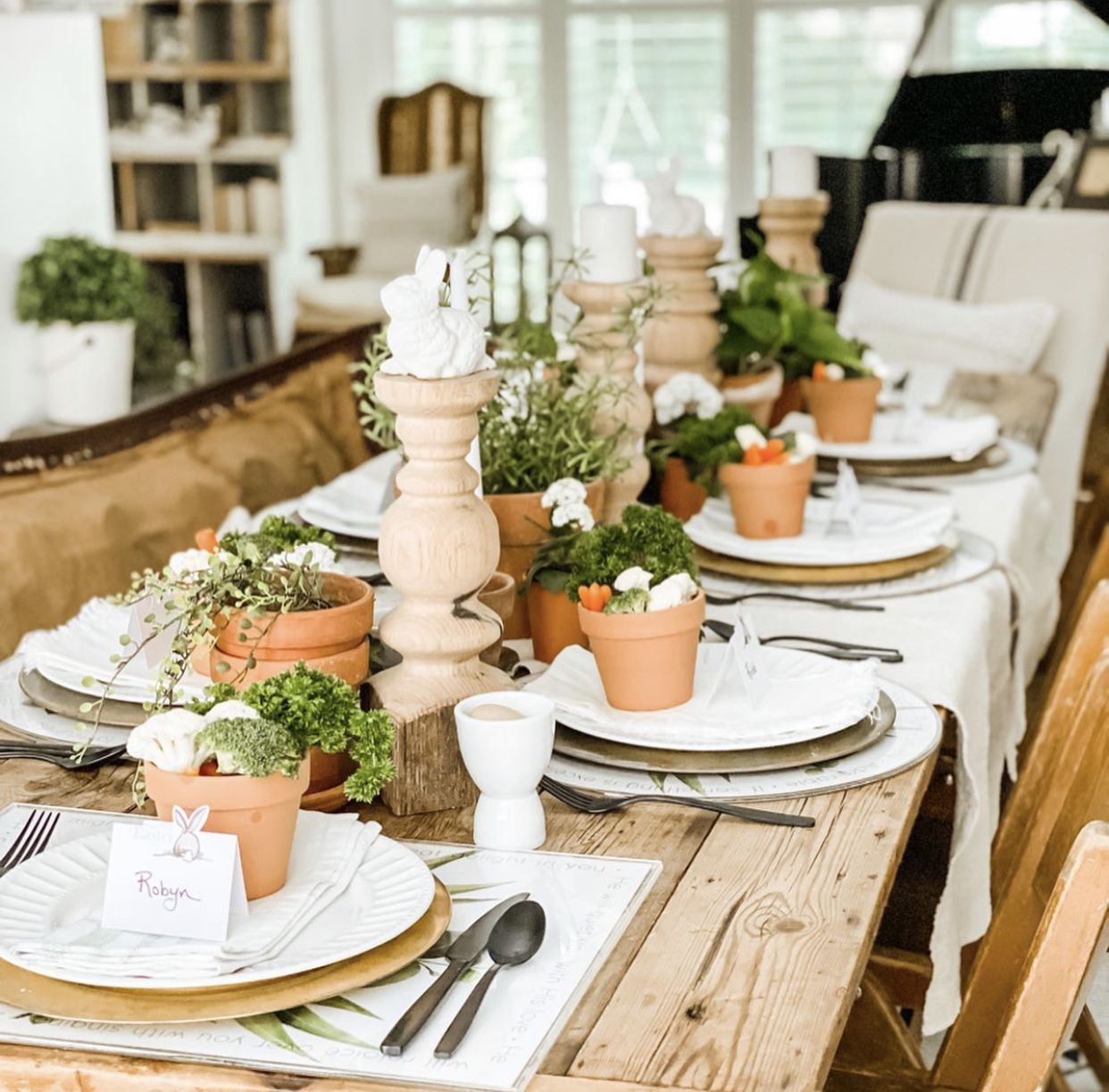 Easter holiday dining room table setting with live plants and decorative candle stick holders.