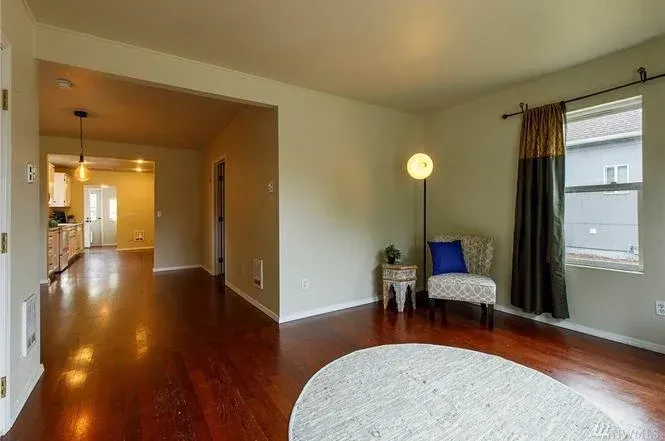 Fresh, cream-colored  paint with white trim contrasts warm wood floors in an upstairs sitting room.