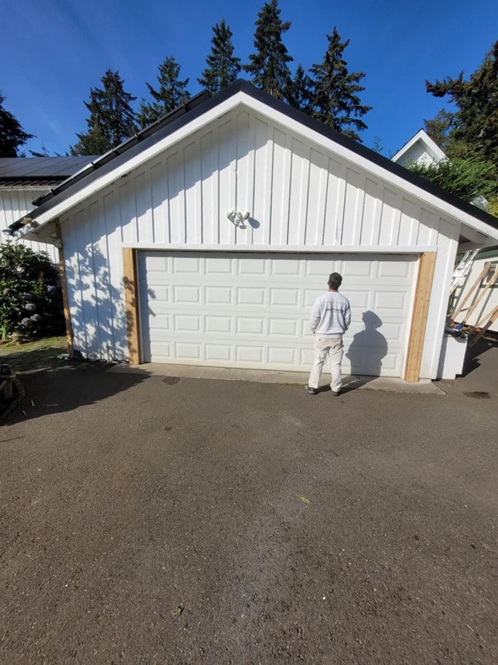A Paint-Right Painting painter inspects a freshly painted white garage and the unfinished trim around the door.