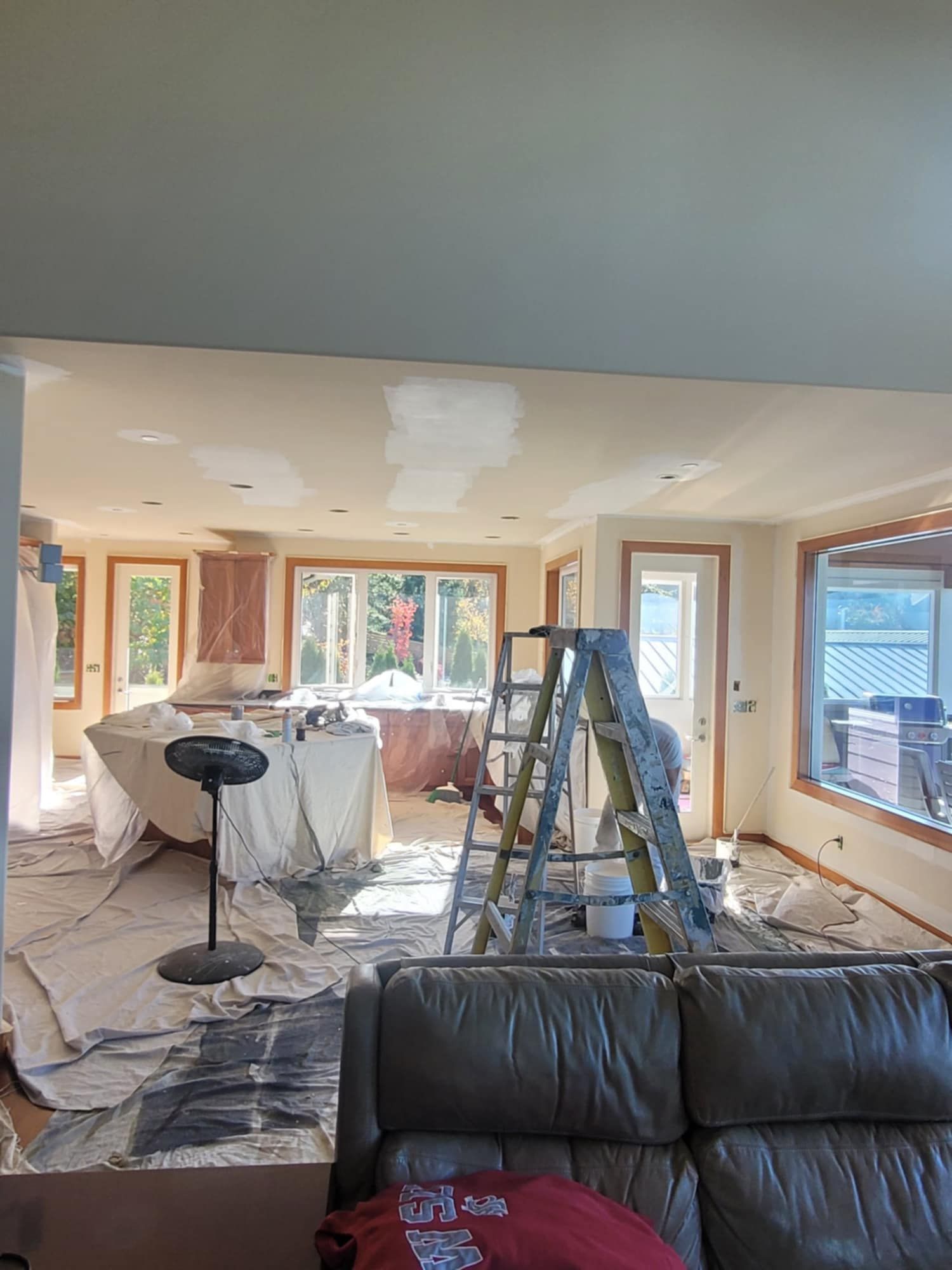 A dining room is emptied and covered in preparation for painting, while the adacent living roo remains intact