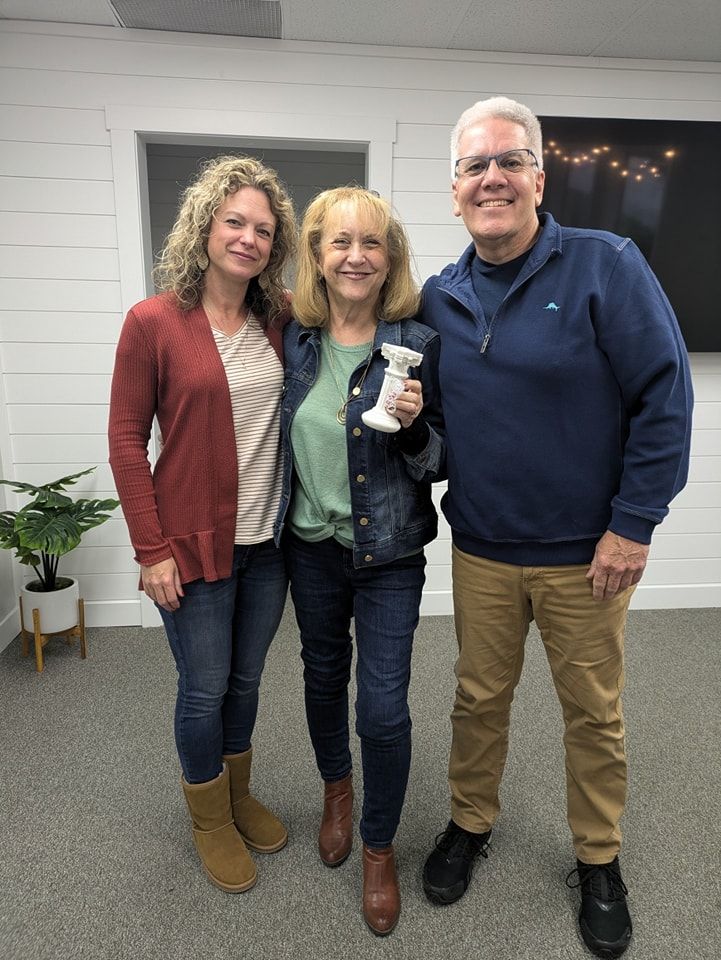 Photo of three people with Kathy Wright in the middle holding a white pillar award. 