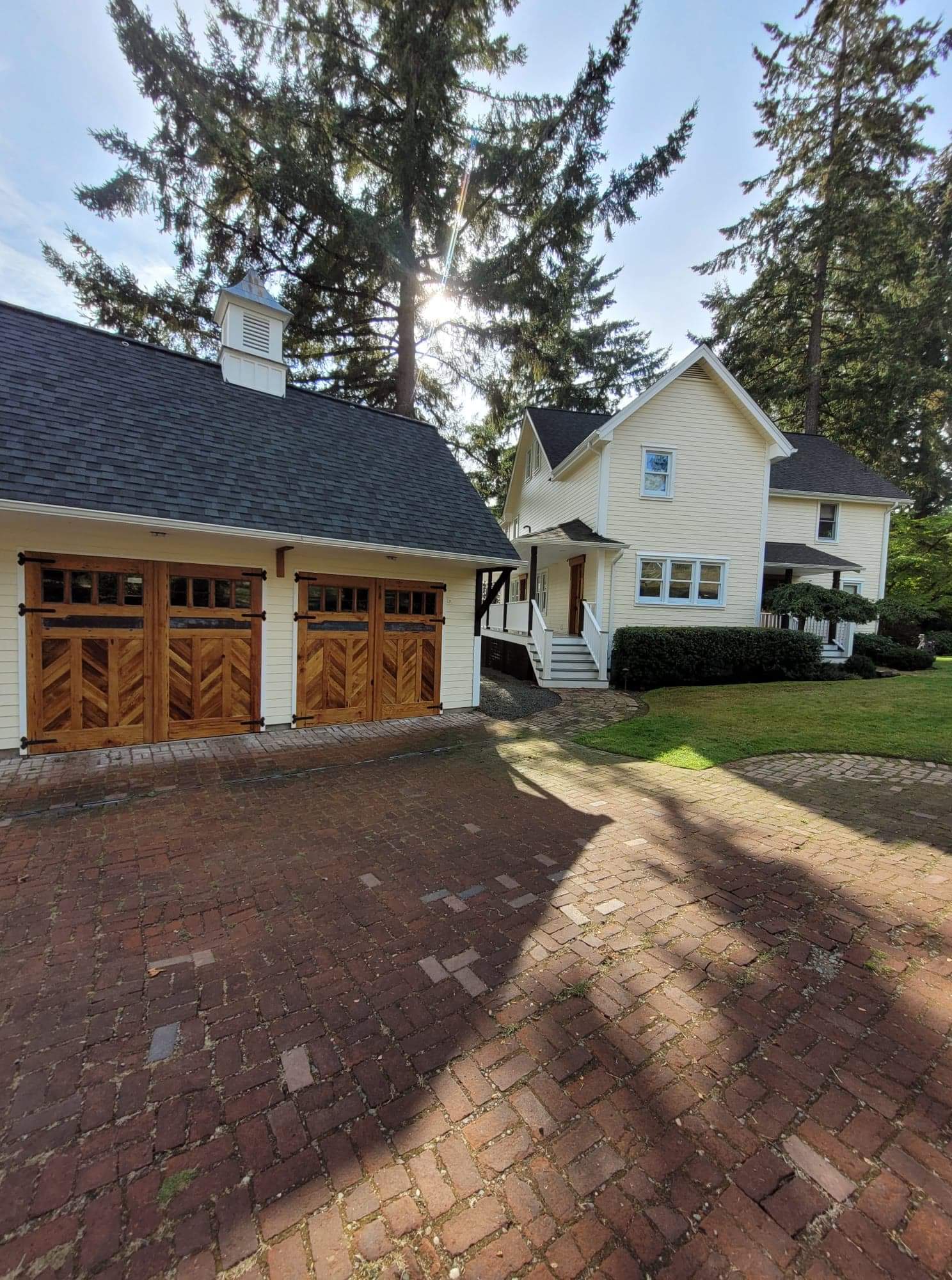 A light yellow house and matching garage with wooden garage accent doors. 