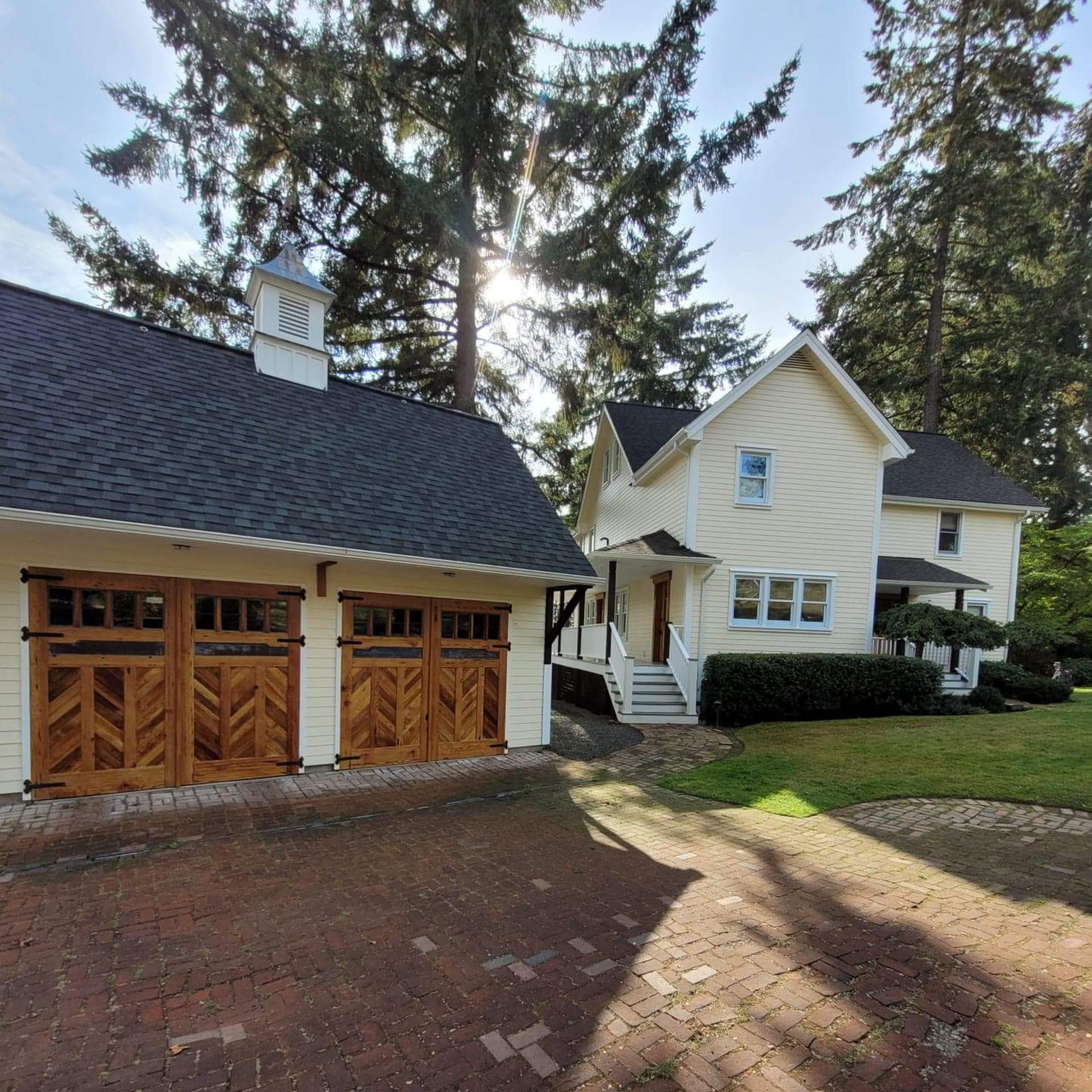 A pale yellow house and matching two-car garage sit behind a long driveway and front lawn.