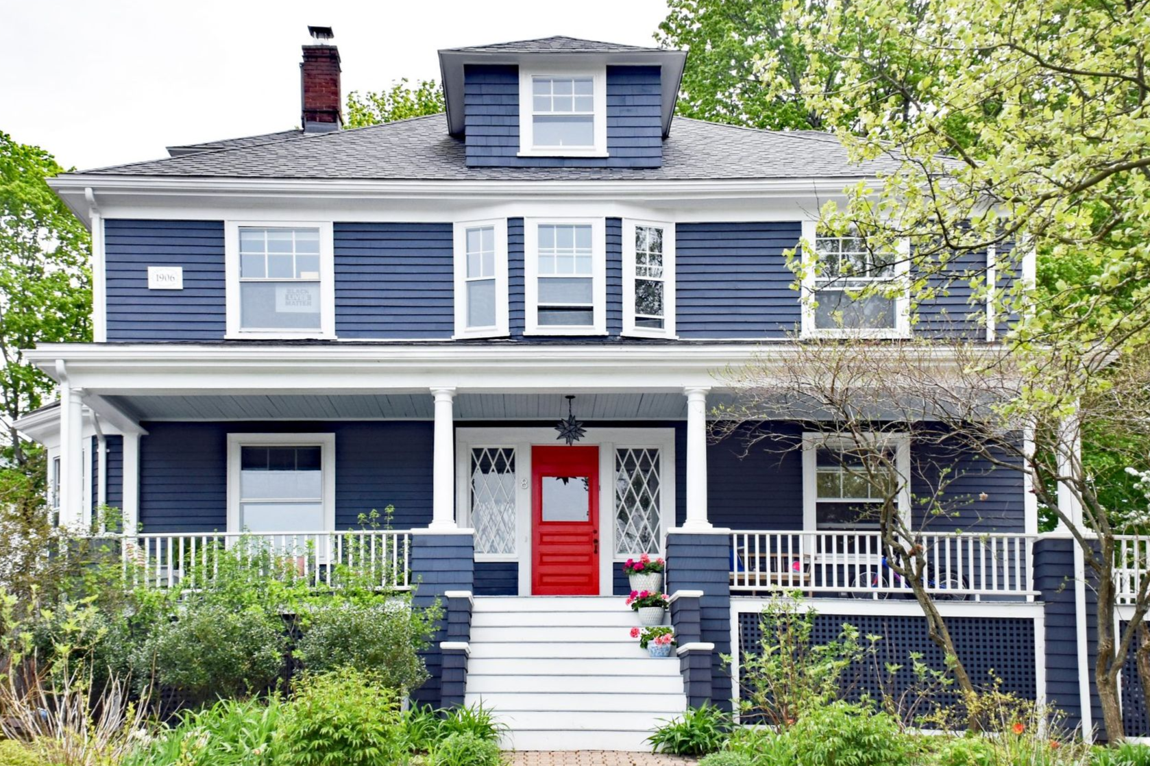 Two-story blue house with white trim, a red front door, and a porch.