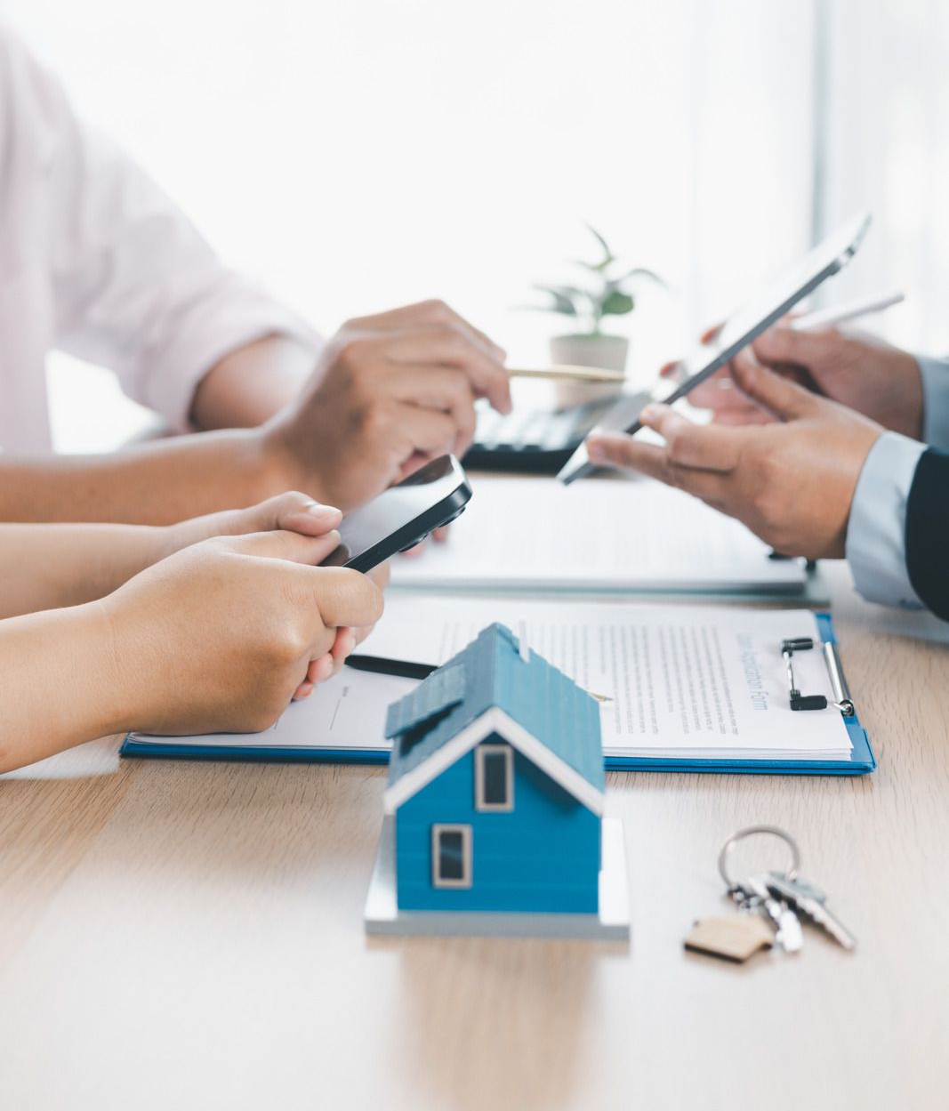 Hands discussing a house model and documents during a real estate meeting